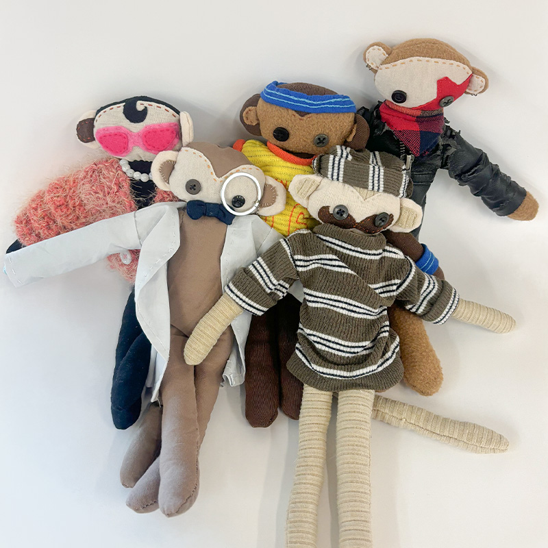 A group of five plush monkeys. A doctor, a rockstar, a fashionista, a basketball player, and a hipster