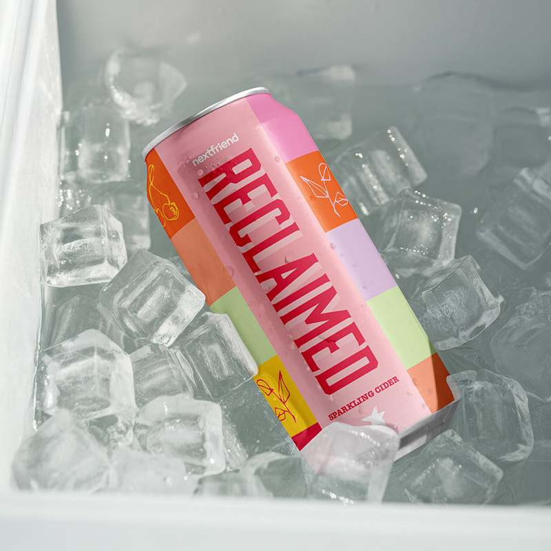 A tall, colourful can of Next Friend's Reclaimed cider lying in a cooler full of ice